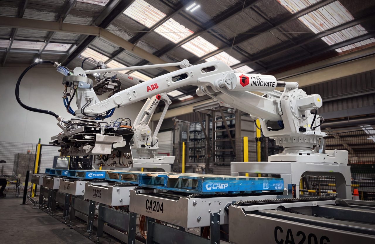 Robotic crate depalletizer being built in the PHS Innovate workshop, its crate pick-up head above a pallet conveyor line