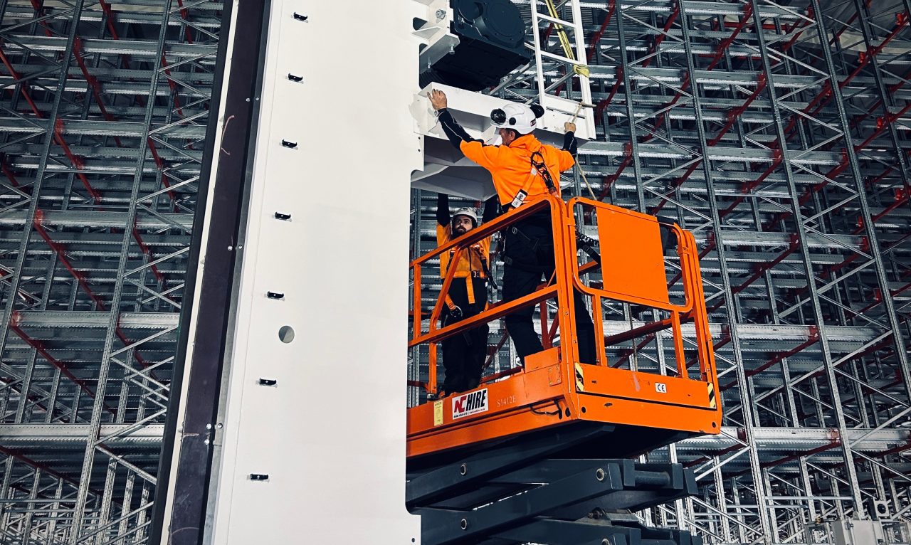 PHS Innovate engineers installing a stacker crane mast inside high-bay racking