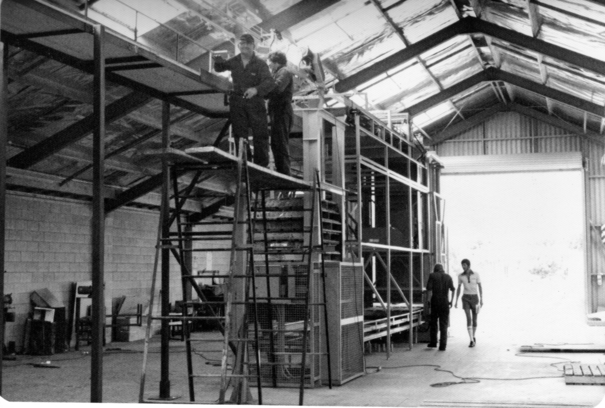 Archive photograph of engineers assembling a materials handling machine in the original PHS workshop