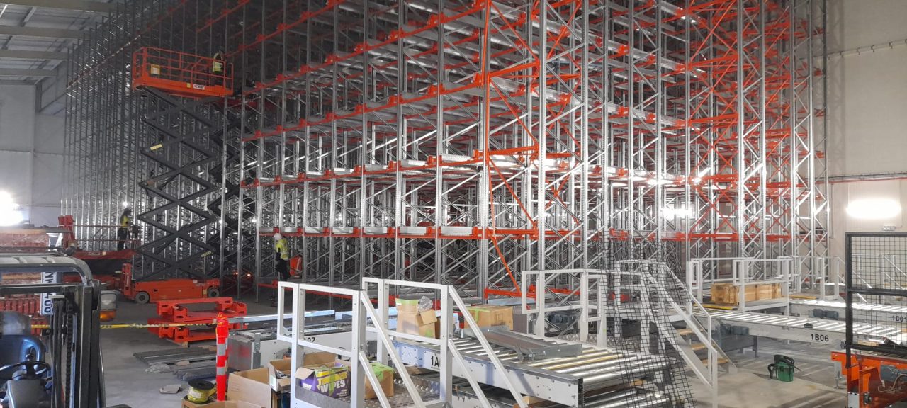 Racking and conveyor being installed for the Foodstuffs South Island automated warehouse, with scissor lifts and crew on site